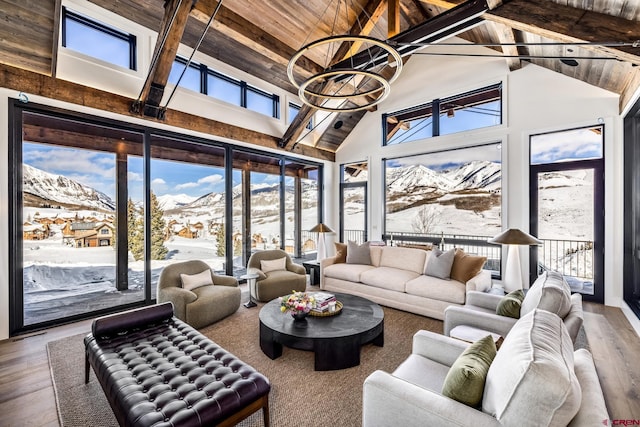 sunroom featuring a mountain view, vaulted ceiling with beams, wooden ceiling, and a healthy amount of sunlight