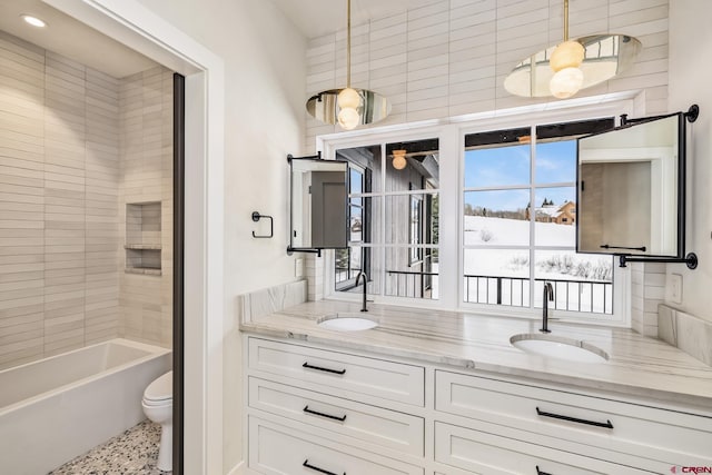 full bathroom featuring vanity, tiled shower / bath, and toilet