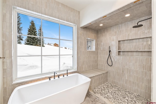 bathroom with a healthy amount of sunlight, independent shower and bath, and tile walls