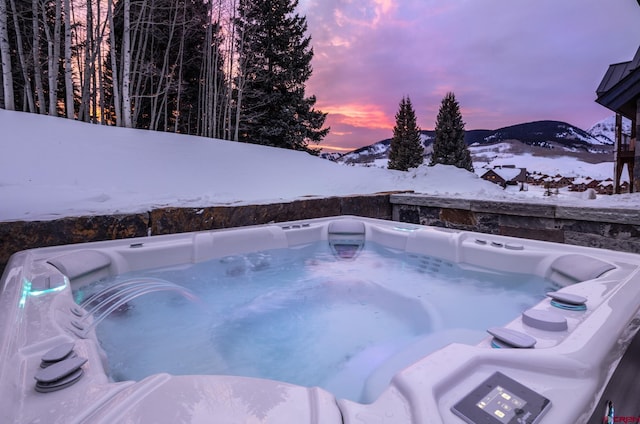 snow covered pool with a hot tub and a mountain view