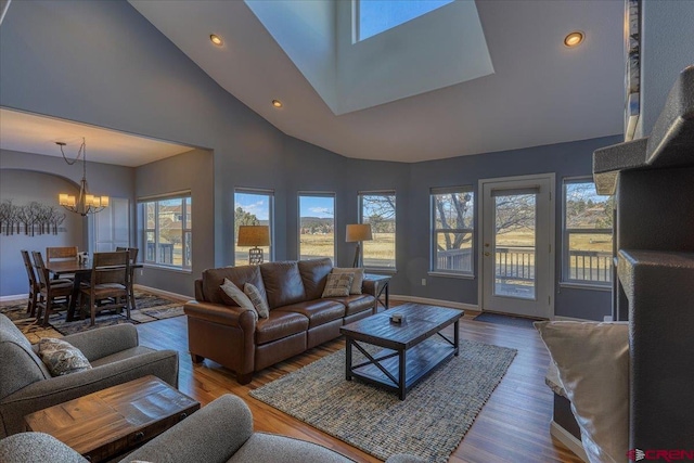 living room with an inviting chandelier, wood-type flooring, and high vaulted ceiling