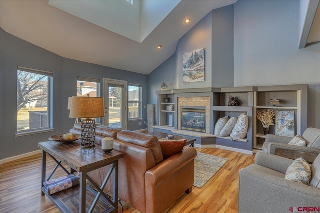 living room with a wealth of natural light, high vaulted ceiling, and light wood-type flooring