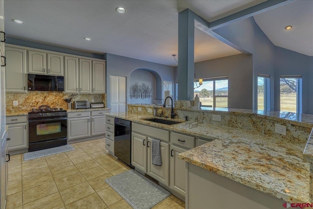 kitchen with sink, tasteful backsplash, light tile patterned floors, light stone countertops, and black appliances