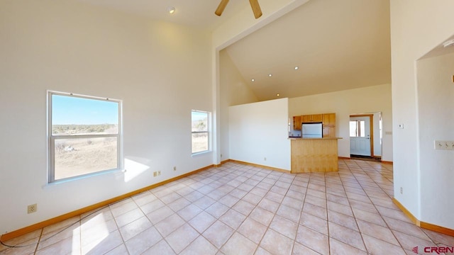 unfurnished living room with ceiling fan, high vaulted ceiling, and light tile patterned floors