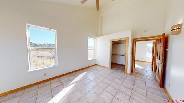 unfurnished bedroom with light tile patterned floors, a walk in closet, and a high ceiling