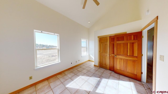 unfurnished bedroom with light tile patterned flooring, ceiling fan, high vaulted ceiling, and a closet