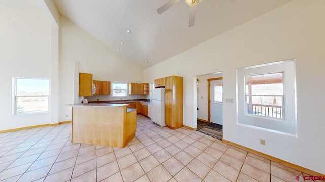 kitchen with light tile patterned floors, ceiling fan, high vaulted ceiling, white refrigerator, and a kitchen island