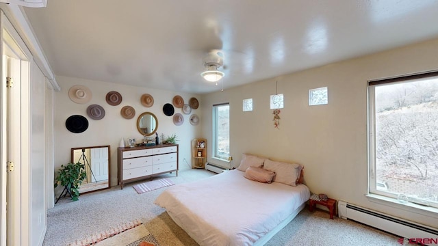 bedroom with ceiling fan, a baseboard radiator, and light carpet