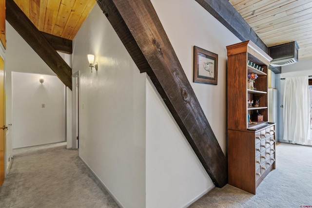 hall with beamed ceiling, a wall mounted air conditioner, light colored carpet, and wooden ceiling