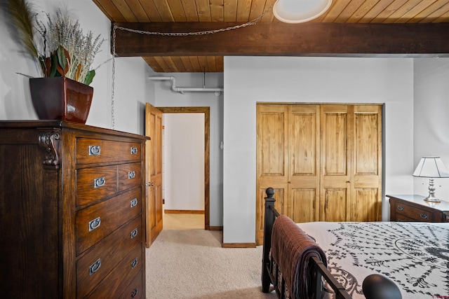 carpeted bedroom featuring beam ceiling, wood ceiling, and a closet