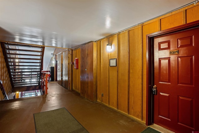 corridor with concrete flooring and wood walls