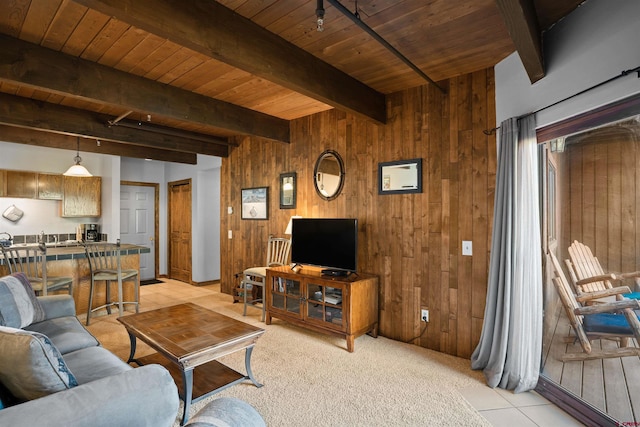 living room featuring beamed ceiling, wooden walls, light carpet, and wooden ceiling