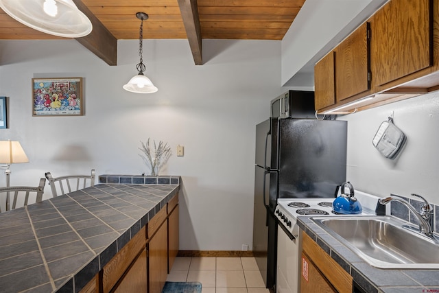 kitchen with hanging light fixtures, light tile patterned flooring, sink, and tile counters