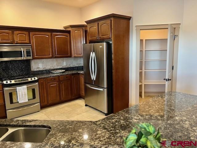 kitchen featuring tasteful backsplash, appliances with stainless steel finishes, and dark stone counters