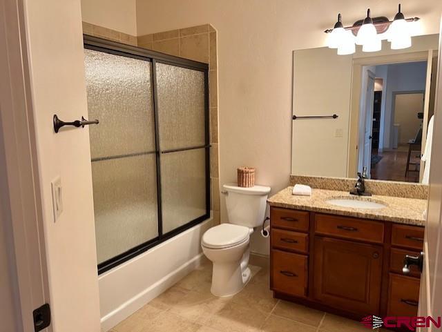 full bathroom featuring vanity, tile patterned flooring, shower / bath combination with glass door, and toilet