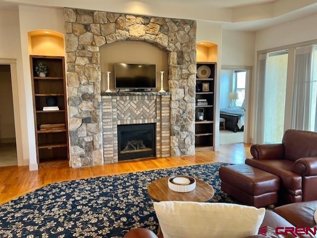 living room featuring hardwood / wood-style flooring, a fireplace, and built in features