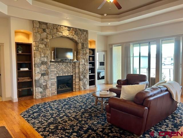 living room featuring hardwood / wood-style floors, a fireplace, built in features, and ceiling fan