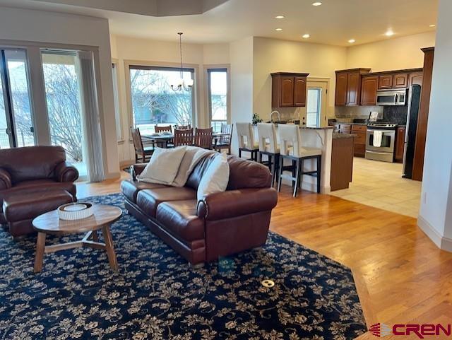 living room featuring an inviting chandelier, a wealth of natural light, and light hardwood / wood-style floors