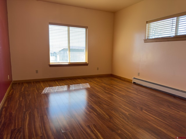 spare room with dark wood-type flooring and a baseboard radiator