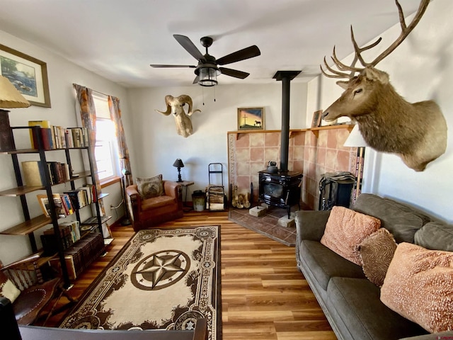 living room featuring ceiling fan, wood-type flooring, and a wood stove