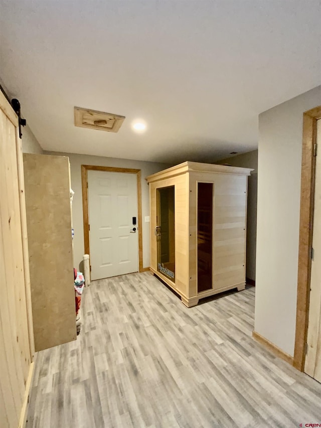 hall with a barn door and light hardwood / wood-style flooring