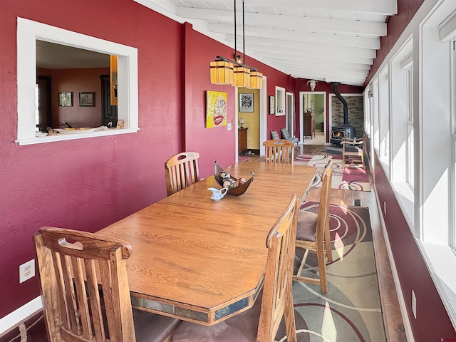 dining space featuring lofted ceiling with beams and a wood stove