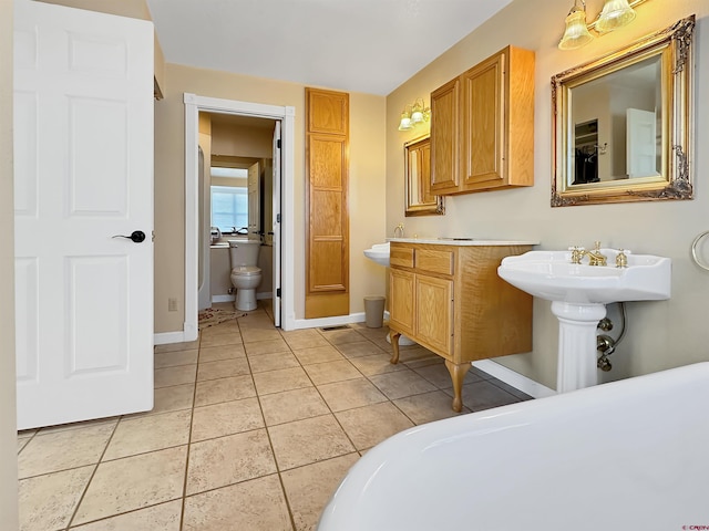 bathroom featuring a bathing tub, sink, tile patterned floors, and toilet