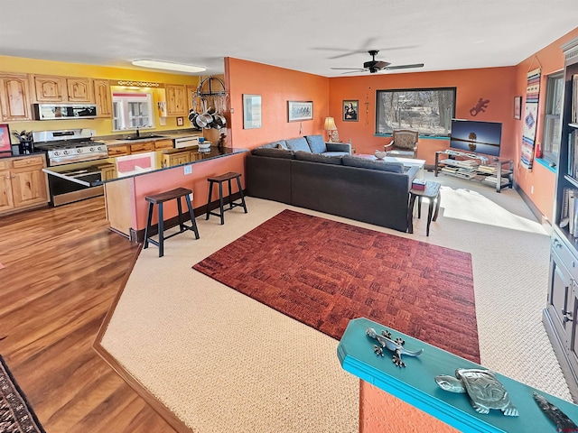 living room featuring ceiling fan, sink, and light wood-type flooring