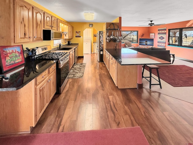 kitchen with a wealth of natural light, washer / clothes dryer, sink, a breakfast bar area, and stainless steel appliances