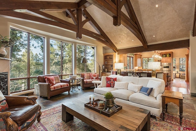 living room with beamed ceiling, a healthy amount of sunlight, an inviting chandelier, and high vaulted ceiling