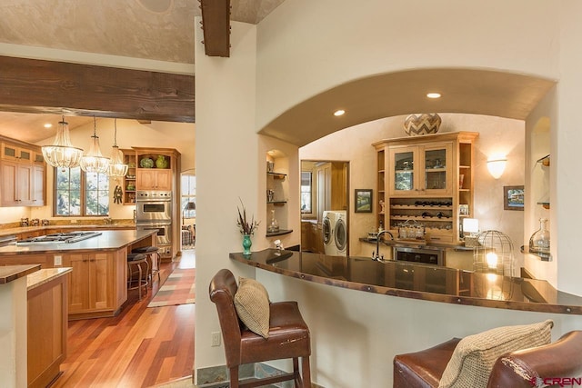 kitchen featuring pendant lighting, separate washer and dryer, kitchen peninsula, and light hardwood / wood-style flooring