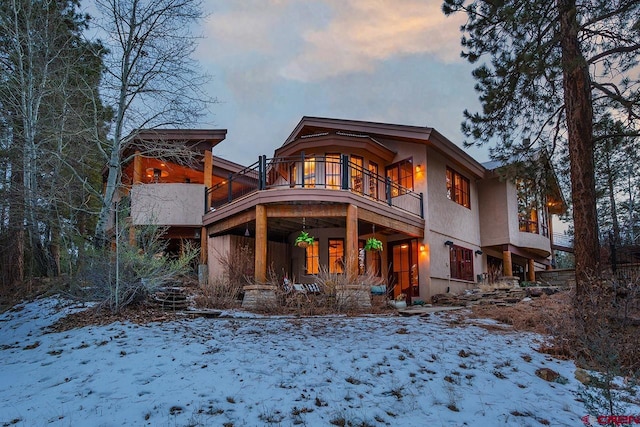 snow covered back of property featuring a balcony