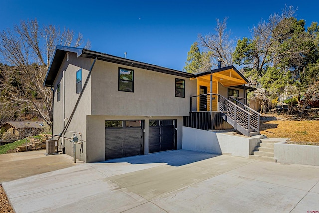 view of front of home featuring an attached garage, stucco siding, central AC unit, and concrete driveway