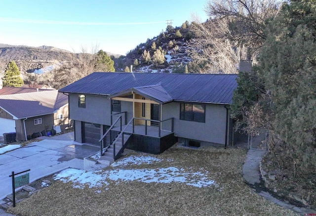 ranch-style house featuring metal roof, a garage, stucco siding, and a mountain view