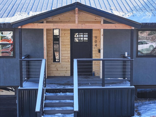 snow covered property entrance featuring metal roof