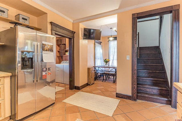 interior space featuring stainless steel refrigerator with ice dispenser, crown molding, washer and dryer, light tile patterned floors, and pendant lighting