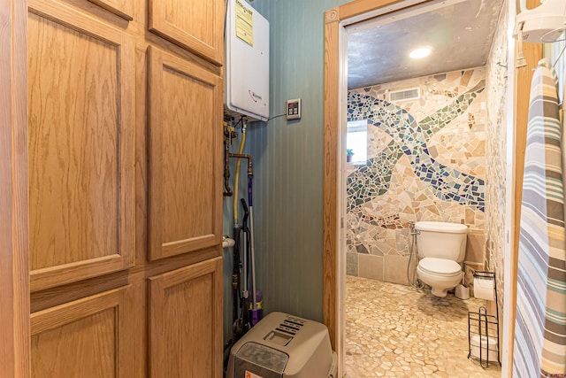 bathroom featuring water heater, tile walls, and toilet