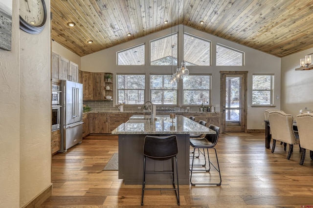 kitchen with stainless steel appliances, light stone countertops, sink, and wooden ceiling