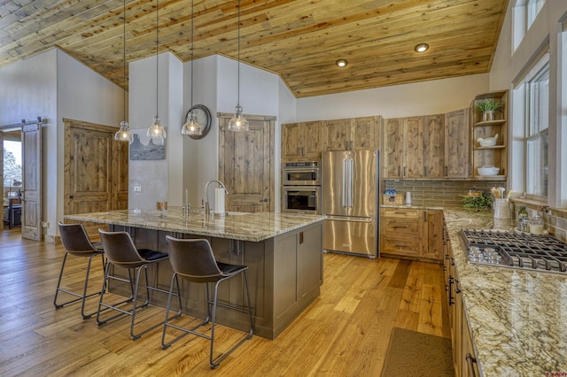 kitchen featuring hanging light fixtures, high vaulted ceiling, an island with sink, and appliances with stainless steel finishes