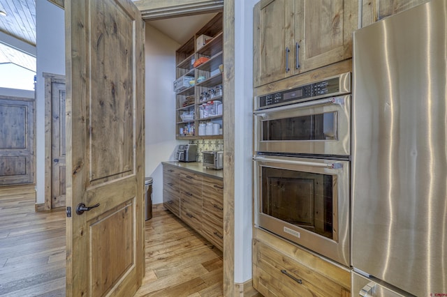 kitchen with appliances with stainless steel finishes and light hardwood / wood-style floors