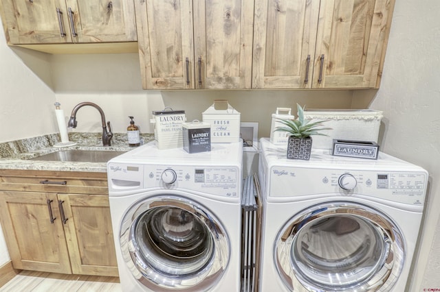 laundry room with cabinets, washing machine and dryer, sink, and light hardwood / wood-style floors