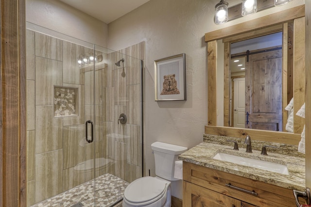 bathroom featuring vanity, a shower with shower door, and toilet