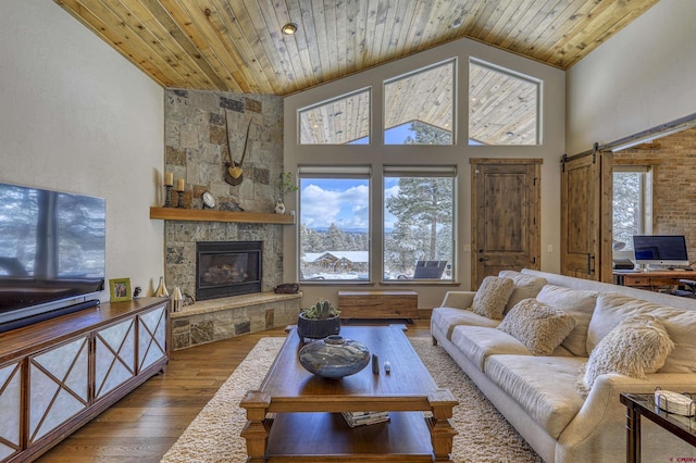 living room with wood ceiling, a healthy amount of sunlight, wood-type flooring, and a stone fireplace