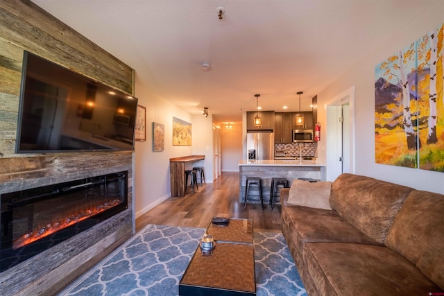 living area featuring a glass covered fireplace, dark wood finished floors, and baseboards