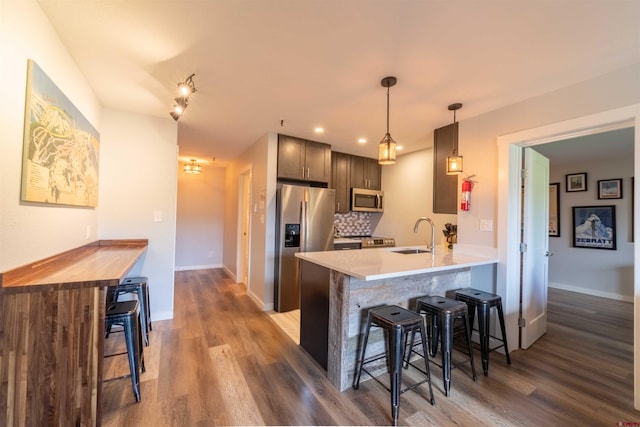 kitchen with stainless steel appliances, light countertops, hanging light fixtures, and a peninsula