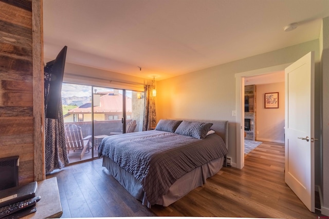 bedroom featuring access to exterior, a fireplace, baseboards, and wood finished floors