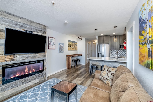 living room with light wood-style floors, a fireplace, a textured ceiling, and baseboards