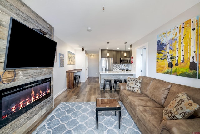 living area with baseboards, wood finished floors, and a glass covered fireplace