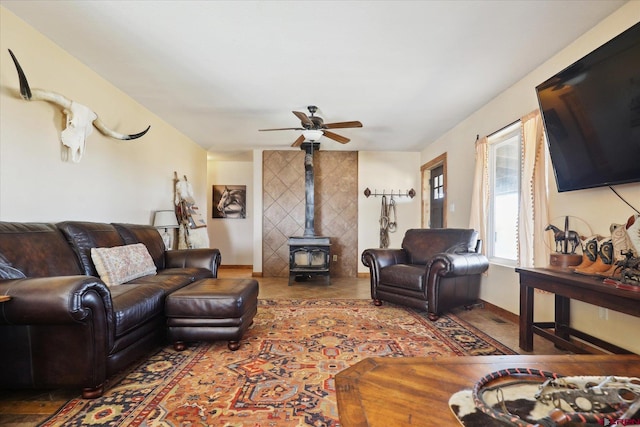 living room featuring a wood stove and ceiling fan