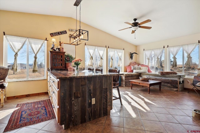 kitchen with ceiling fan, a kitchen breakfast bar, decorative light fixtures, vaulted ceiling, and tile patterned floors